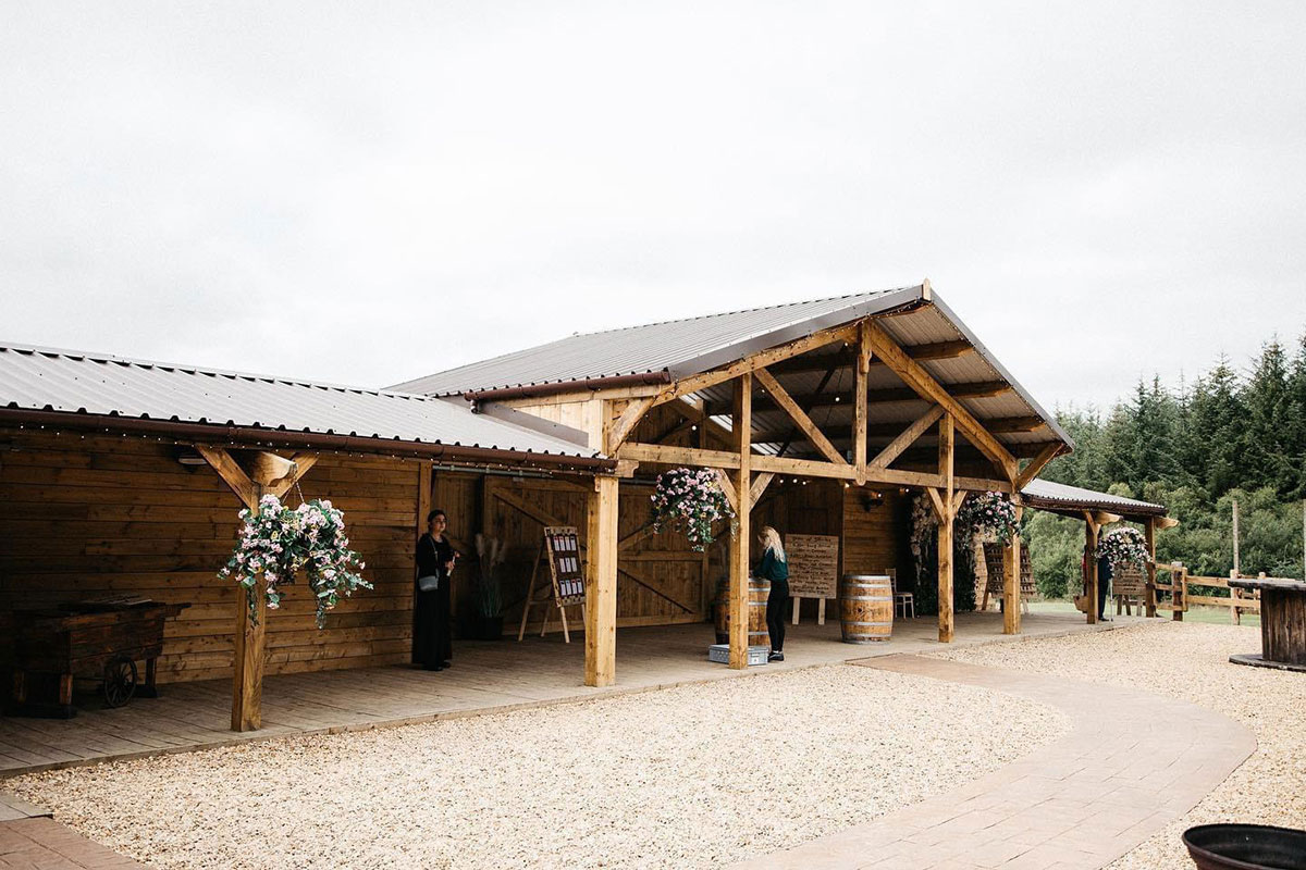 eden leisure village's barn from the outside with hanging basket flowers