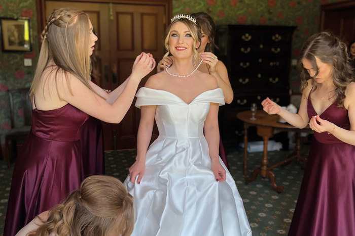 bridesmaids help bride with final touches and jewellery