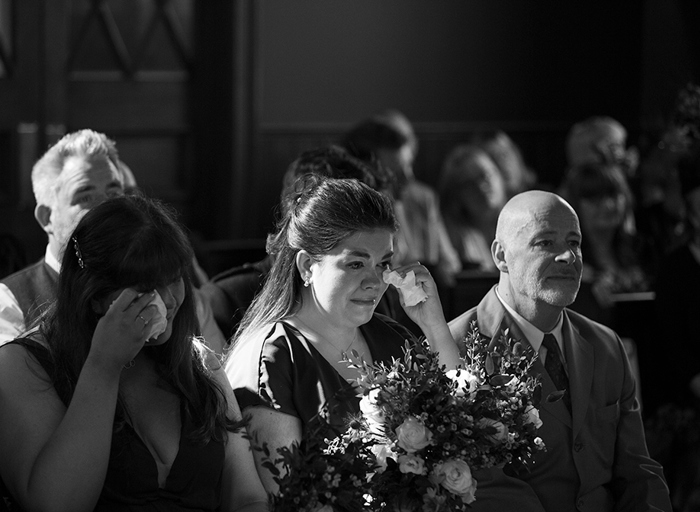 emotional wedding guests seated in a row dab tears away