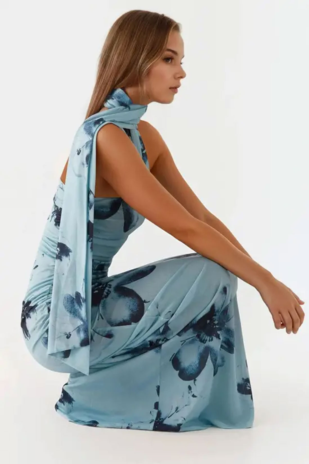 Blue floral printed bodycon maxi dress with matching neck scarf detail styled in a minimalist studio setting