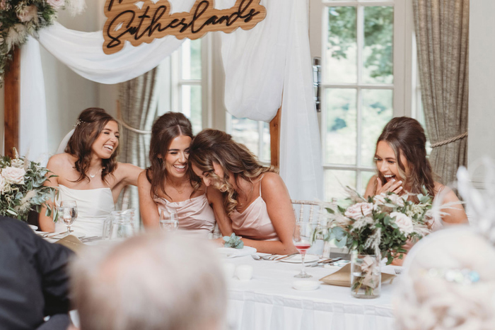Bride and bridesmaids laugh during speeches