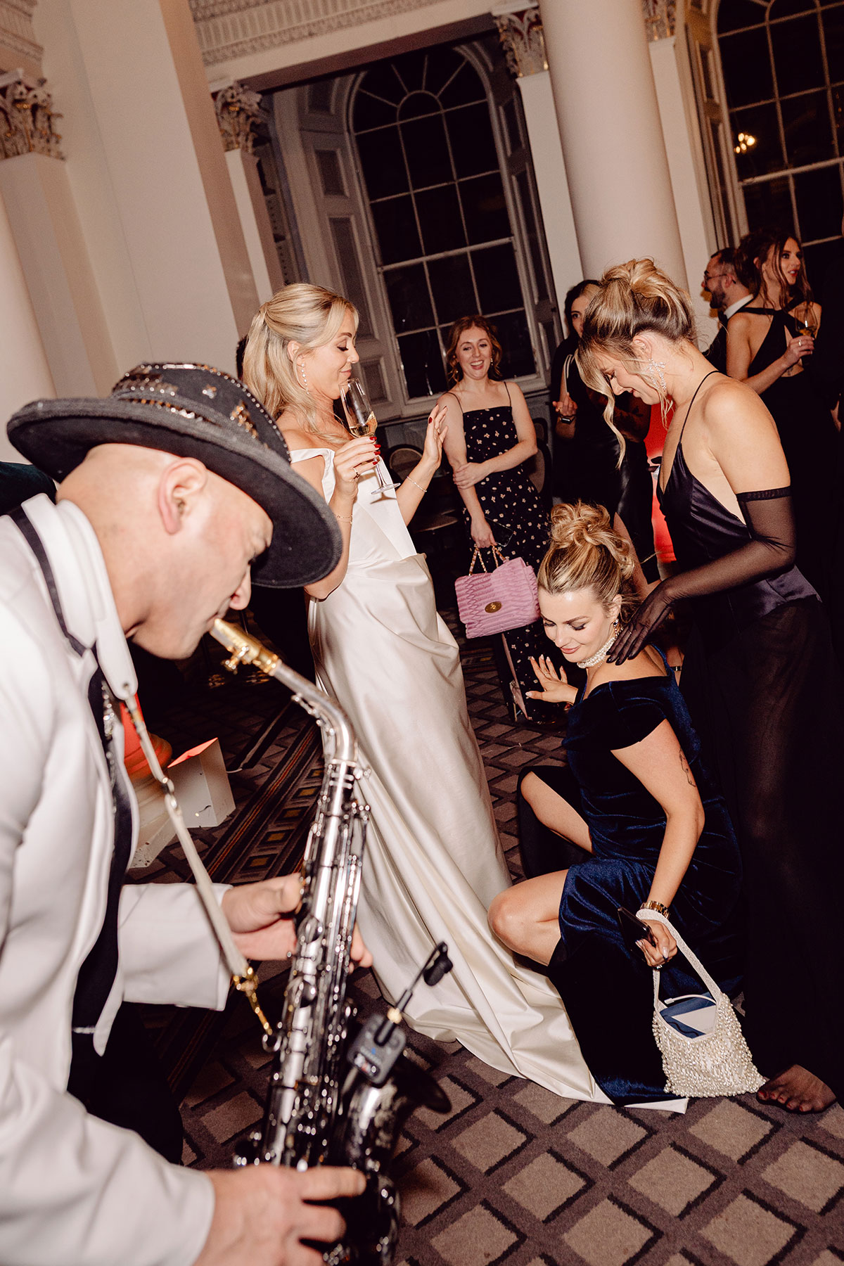Wedding guests dancing at the Signet Library while a saxophonist performs, with the bride celebrating among friends