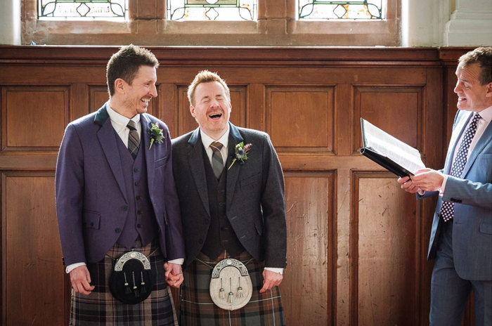 Two grooms laugh during their ceremony