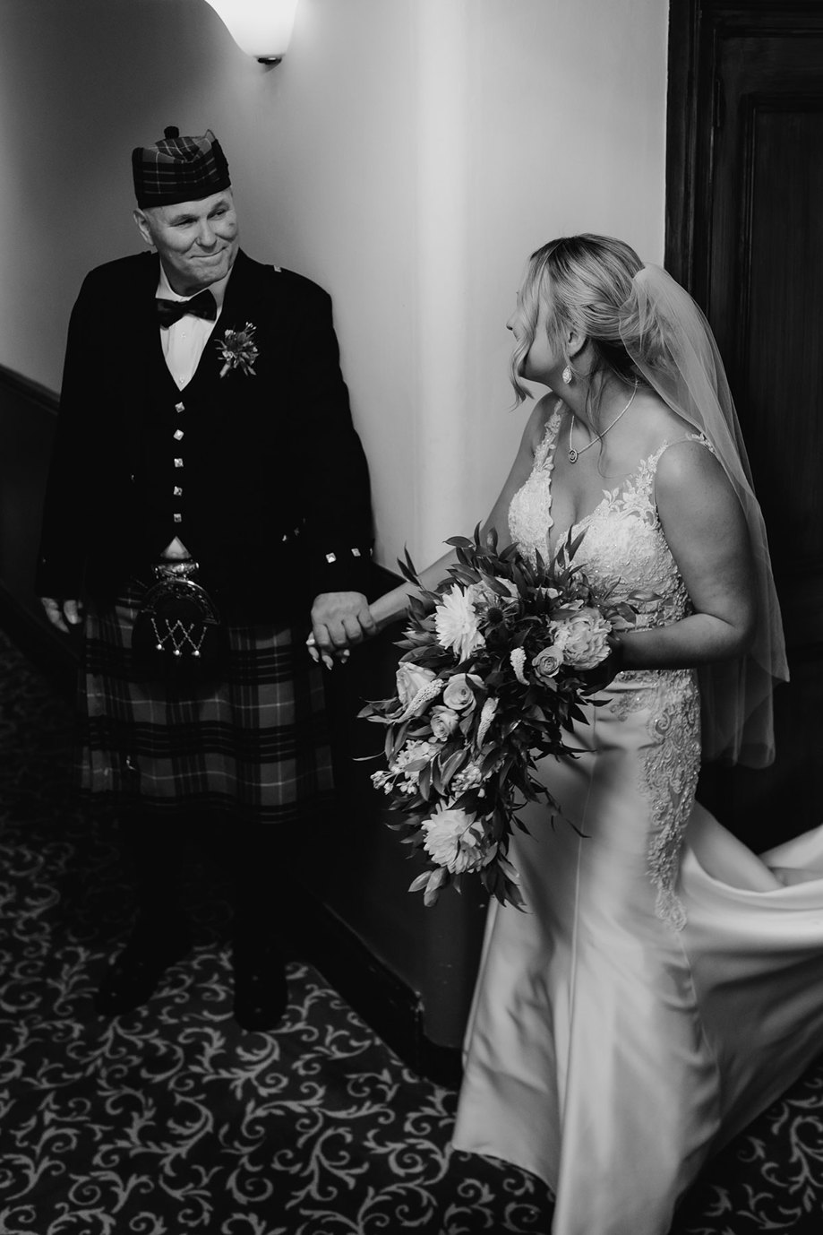  bride and dad hold hands and smile for picture at dalhousie castle