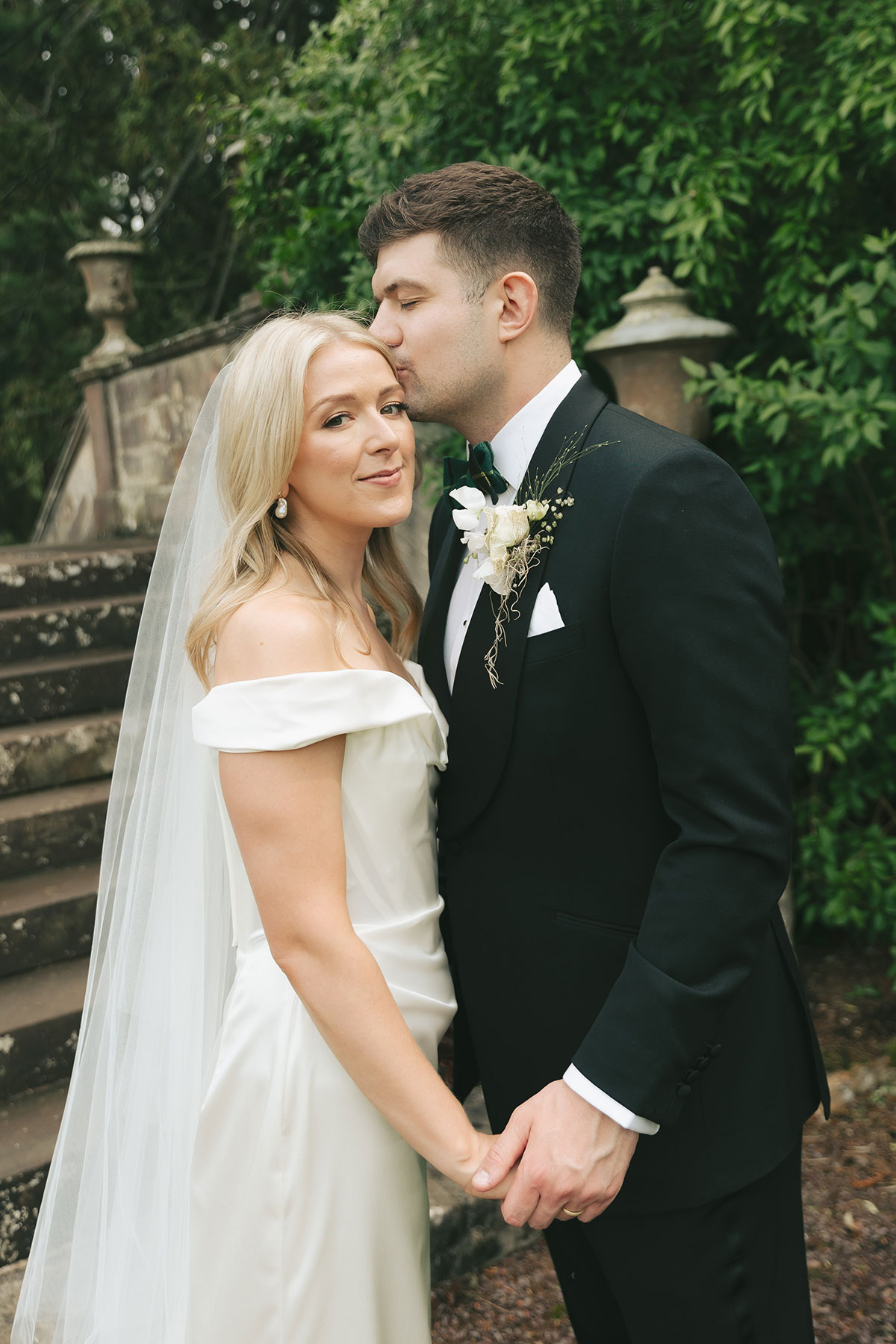 Groom kissing bride on the head in garden at Gilmerton House East Lothian wedding venue