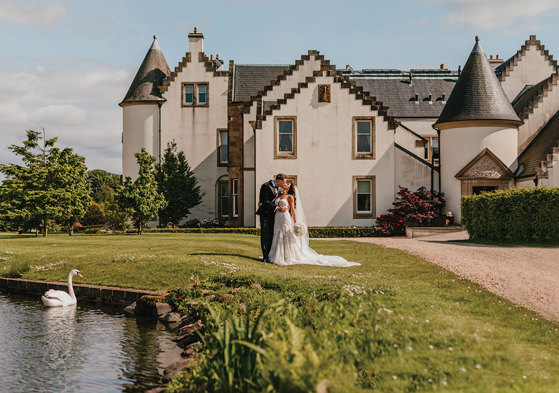 Couple kiss in front of Ingliston Estate and Country Club