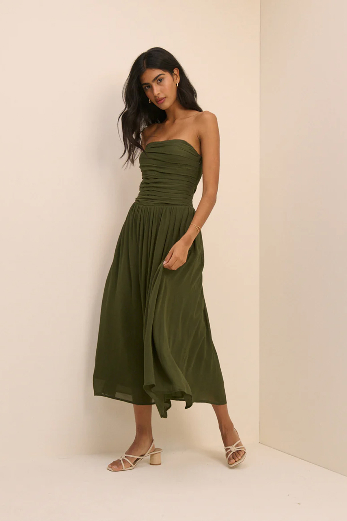 Model wearing a khaki-green bandeau midi dress with a ruched bodice and flowing skirt.