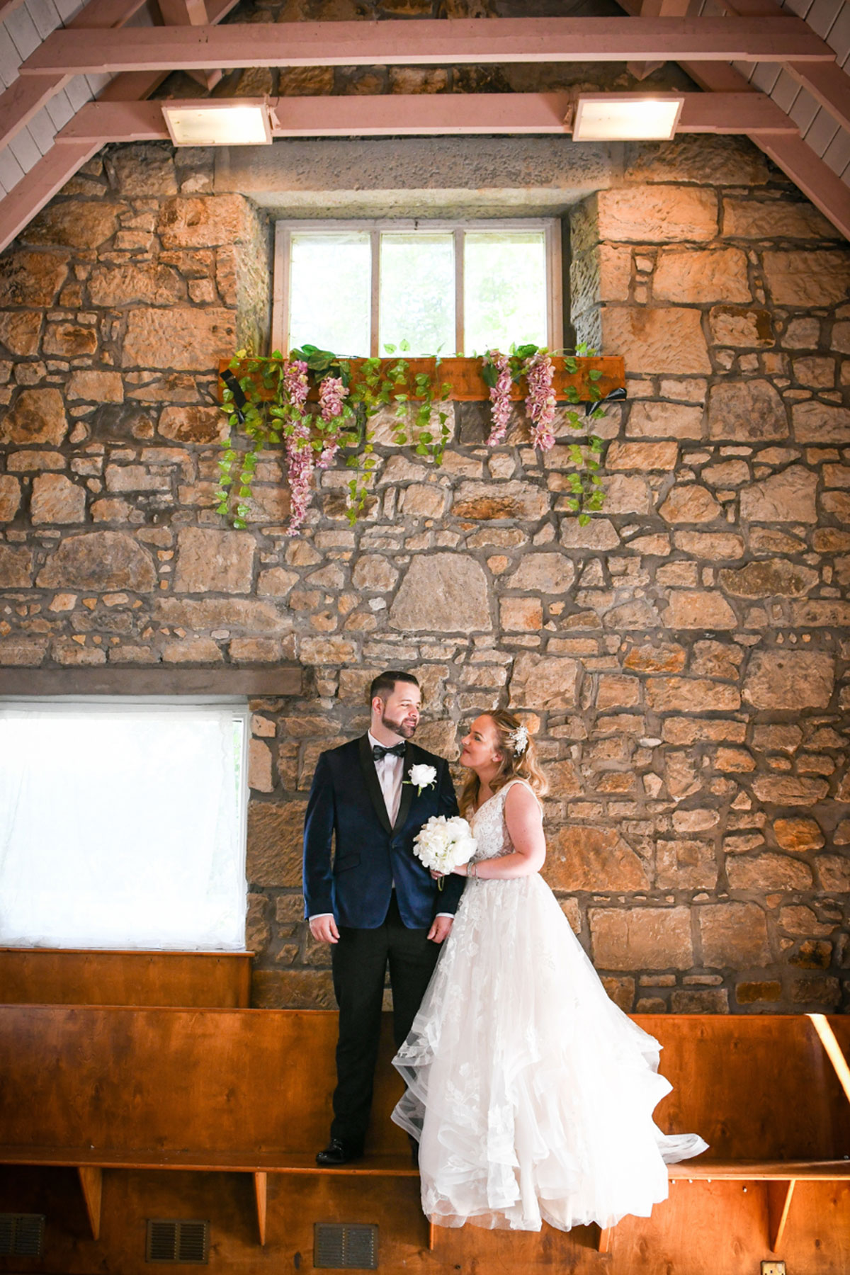 Bride and groom standing inside Geilsland Estate’s stone chapel, with rustic walls and floral decorations.