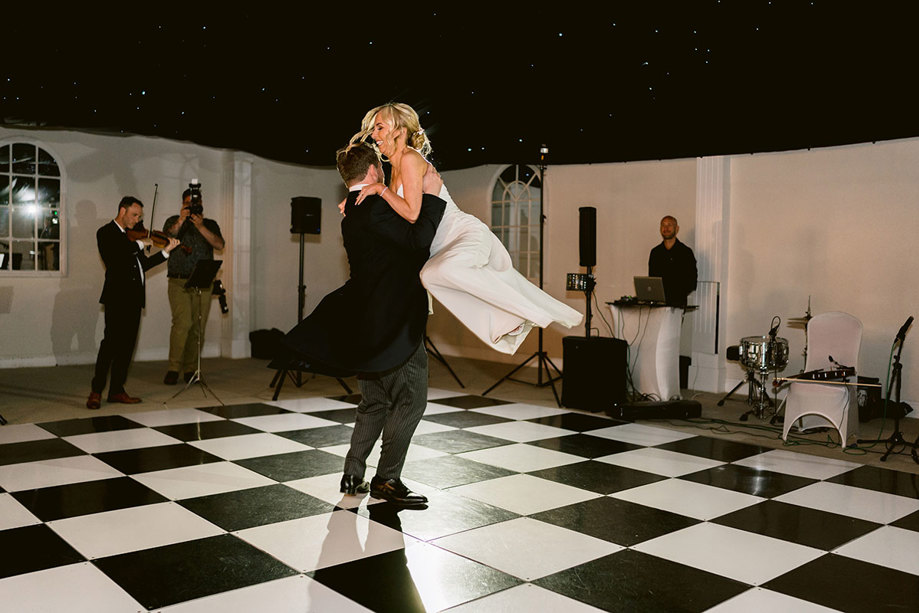 A bride and groom dancing on a checkered floor in the permanent marquee at Mar Hall.