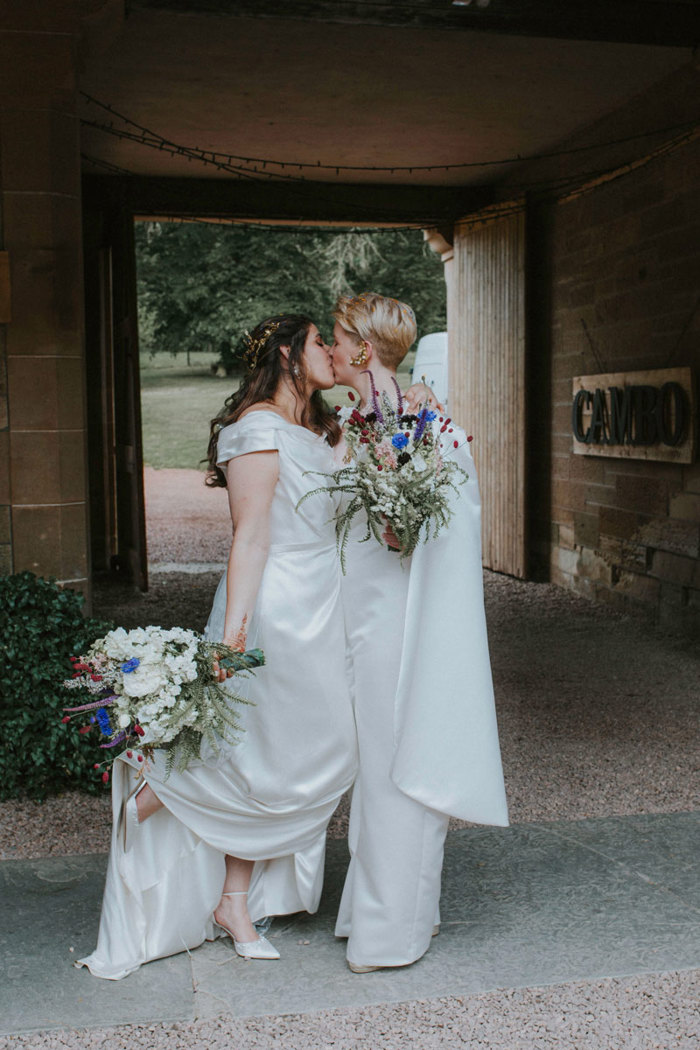 two brides kiss under archway at cambo house and estate