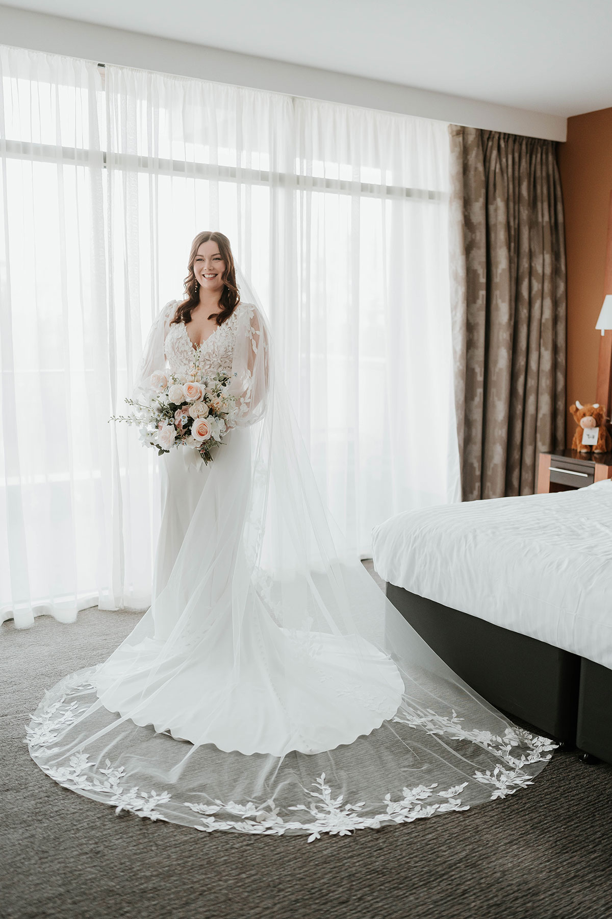 Bride in lace-sleeved gown holding spring bouquet 