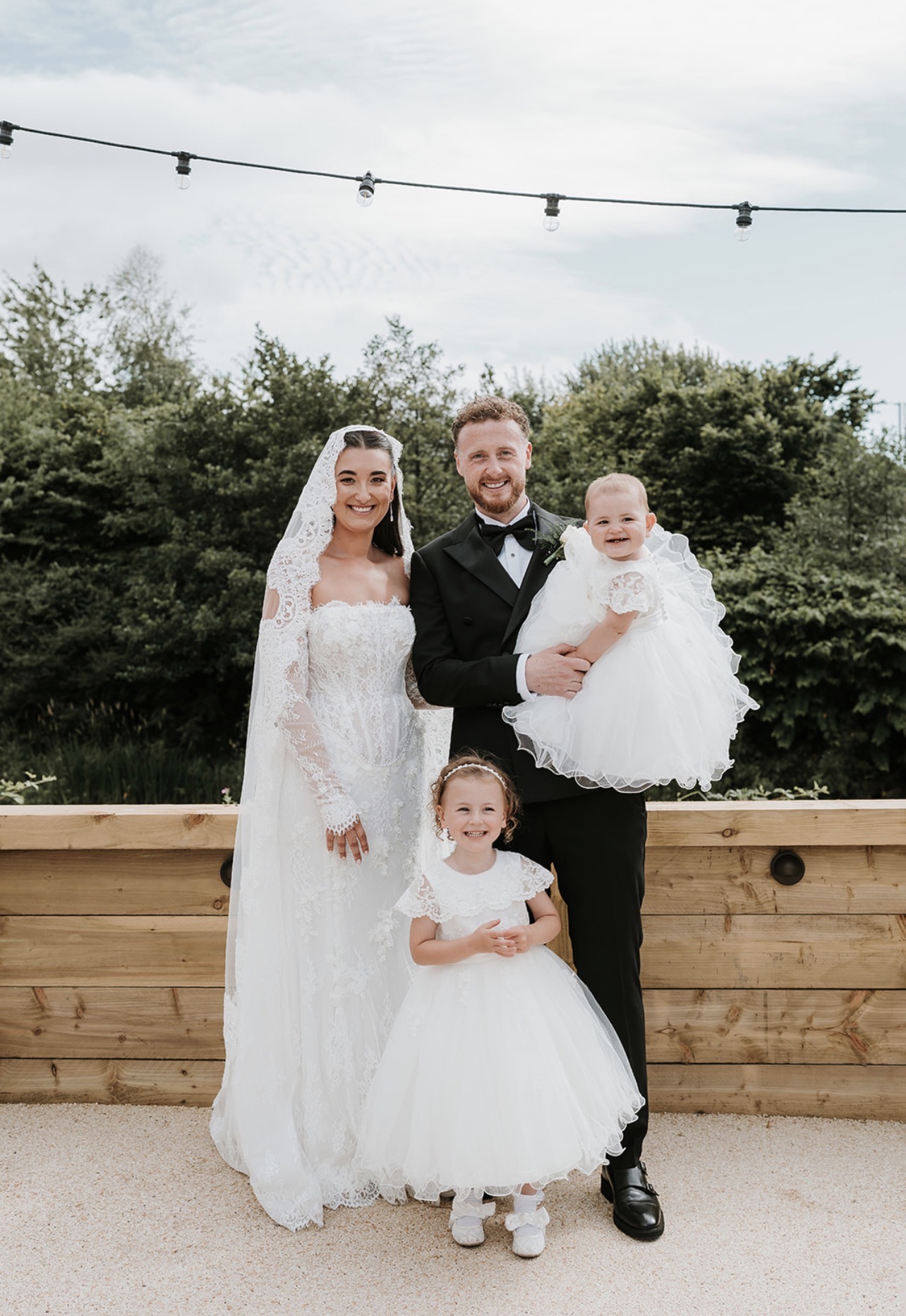 Bride and groom with two young children during an outdoor wedding at The River Inn in Renfrewshire.