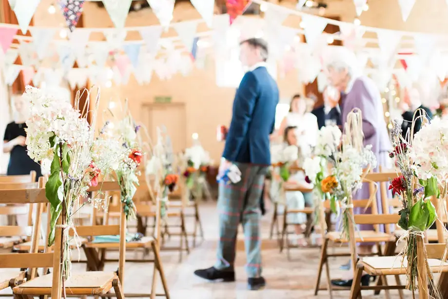 Ceremony set up with wooden chairs and decorated with bunting and florals
