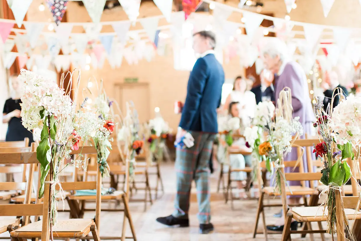 Ceremony set up with wooden chairs and decorated with bunting and florals