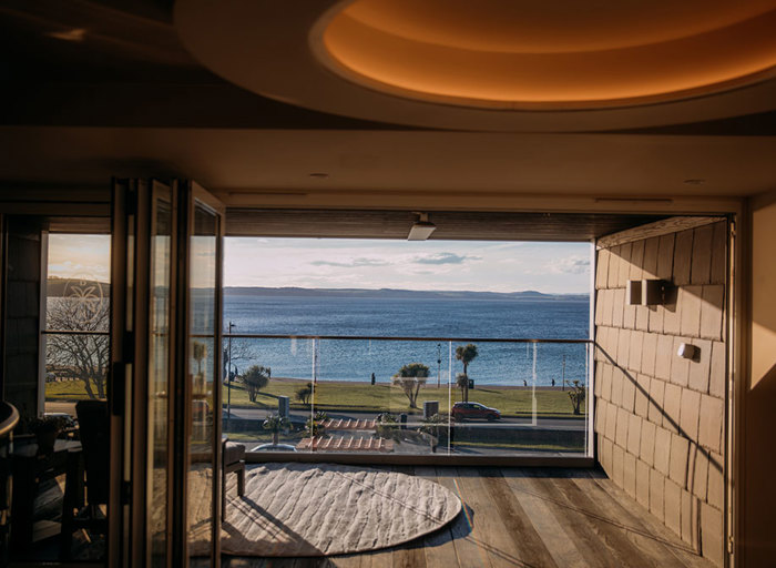Bi-folding doors opened up to show a balcony and a view of the sea