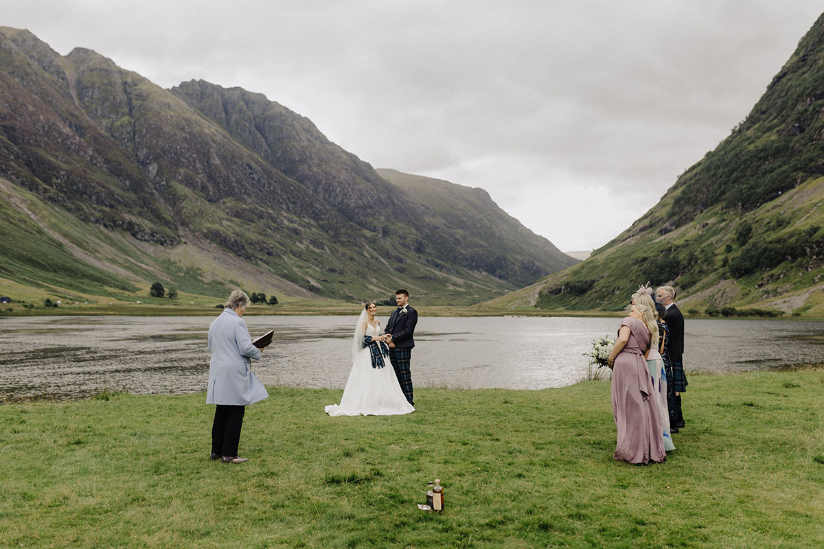 Wedding ceremony taking place with loch and mountains in the background