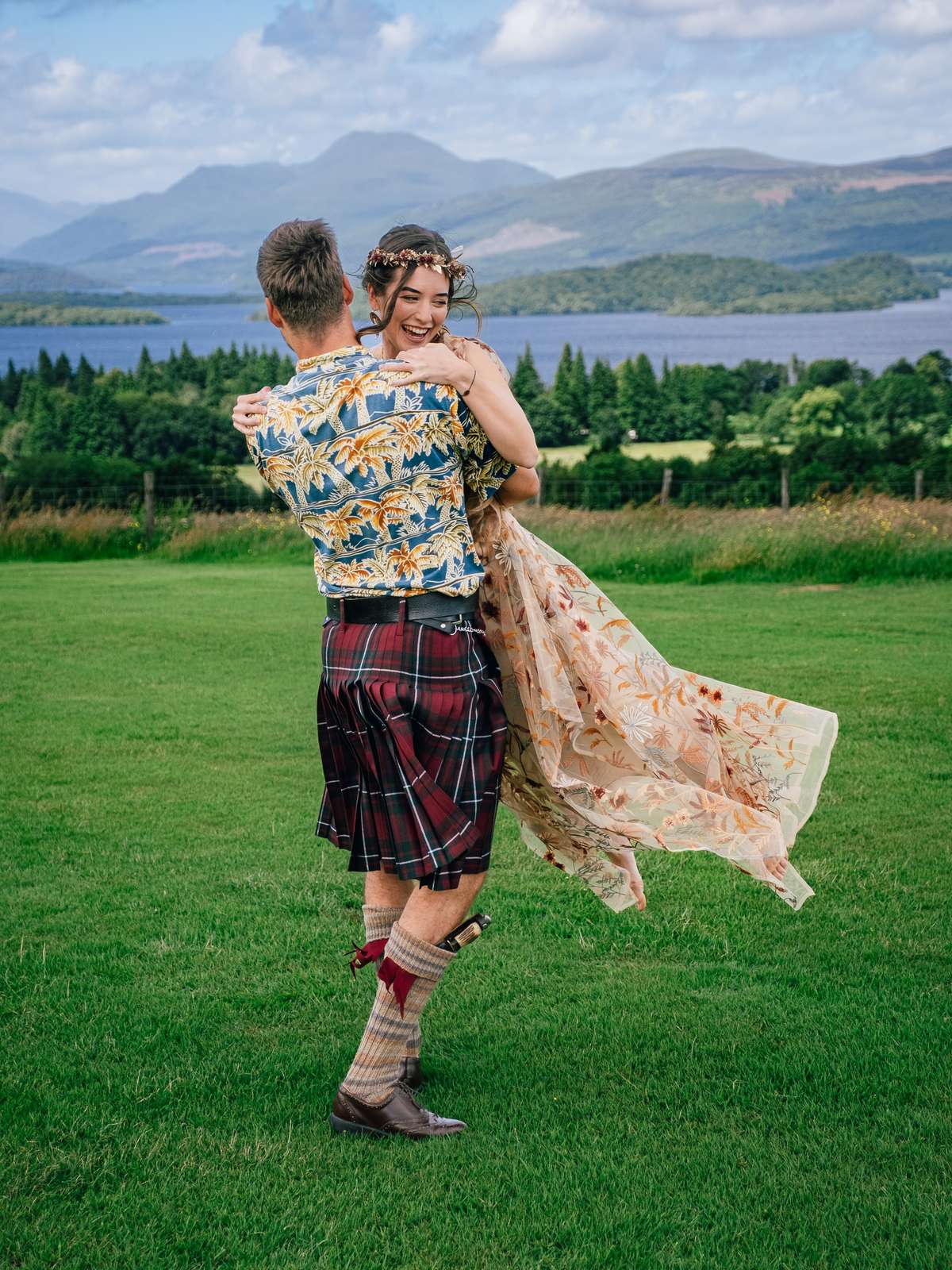 Groom lifting his bride during relaxed wedding portraits on the lawn at Ardoch Loch Lomond