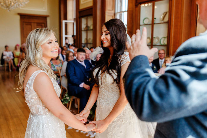Brides hold hands during their ceremony