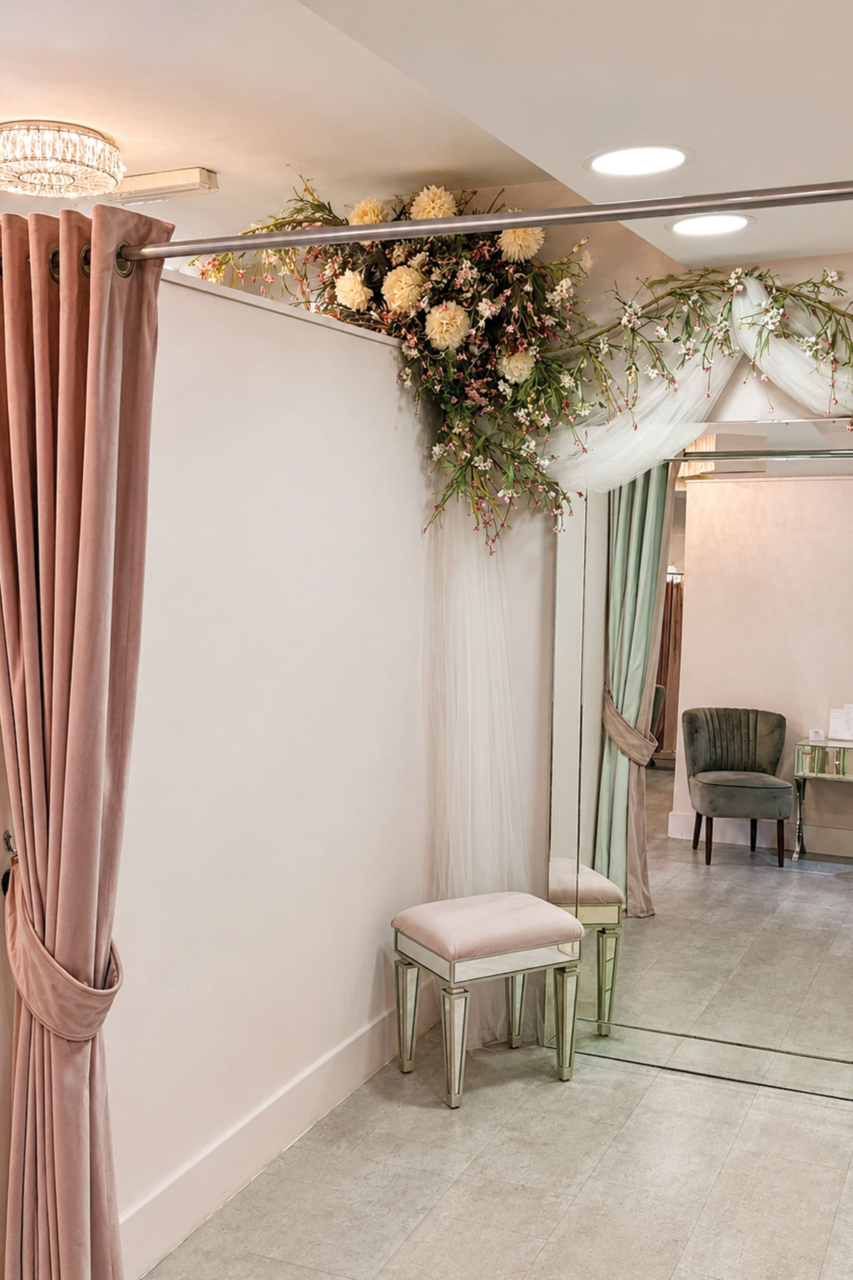 Bridal alterations fitting room with full-length mirrors, pink curtains and floral detailing.