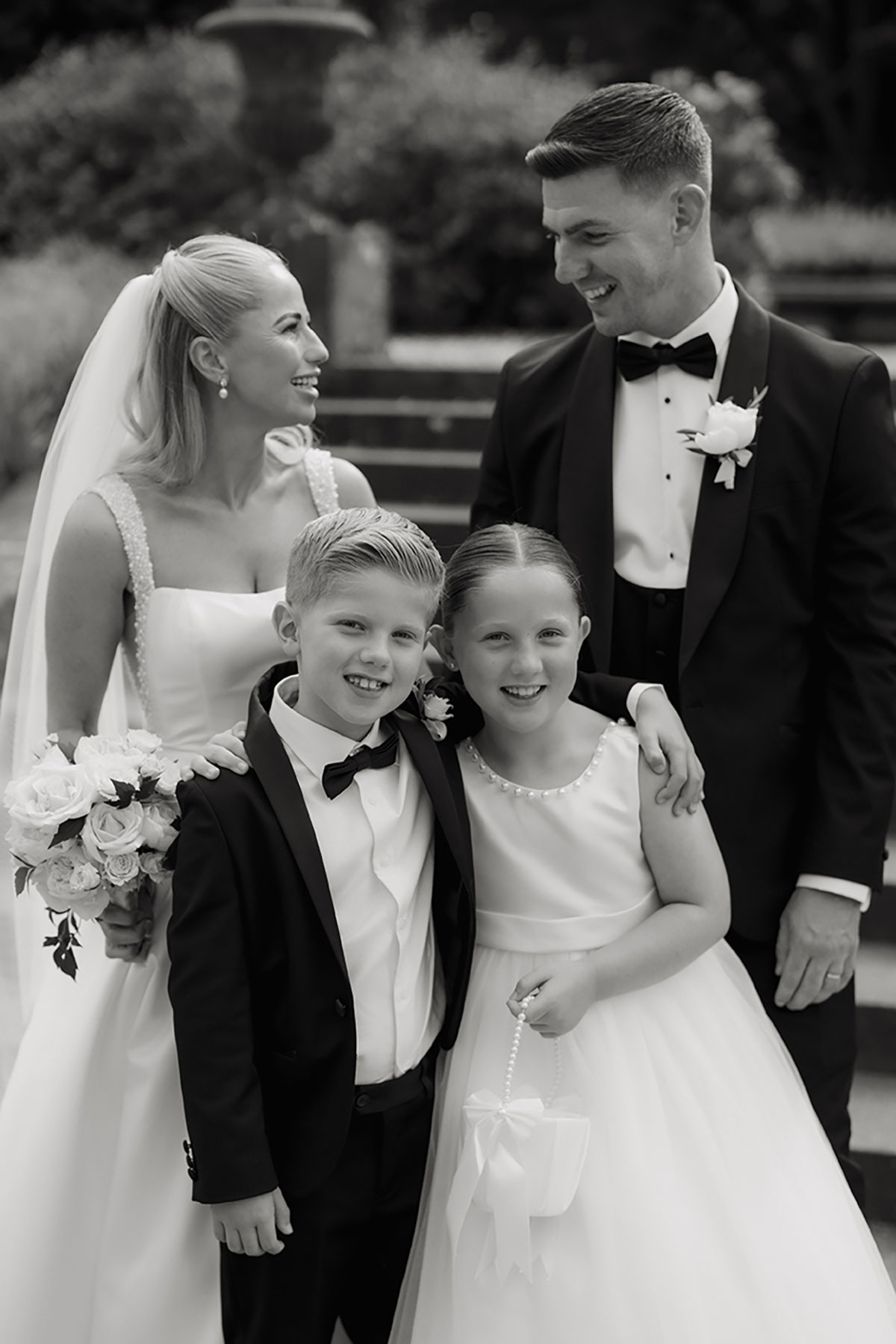 Bride and groom smiling with two children during their wedding portraits at Mar Hall.