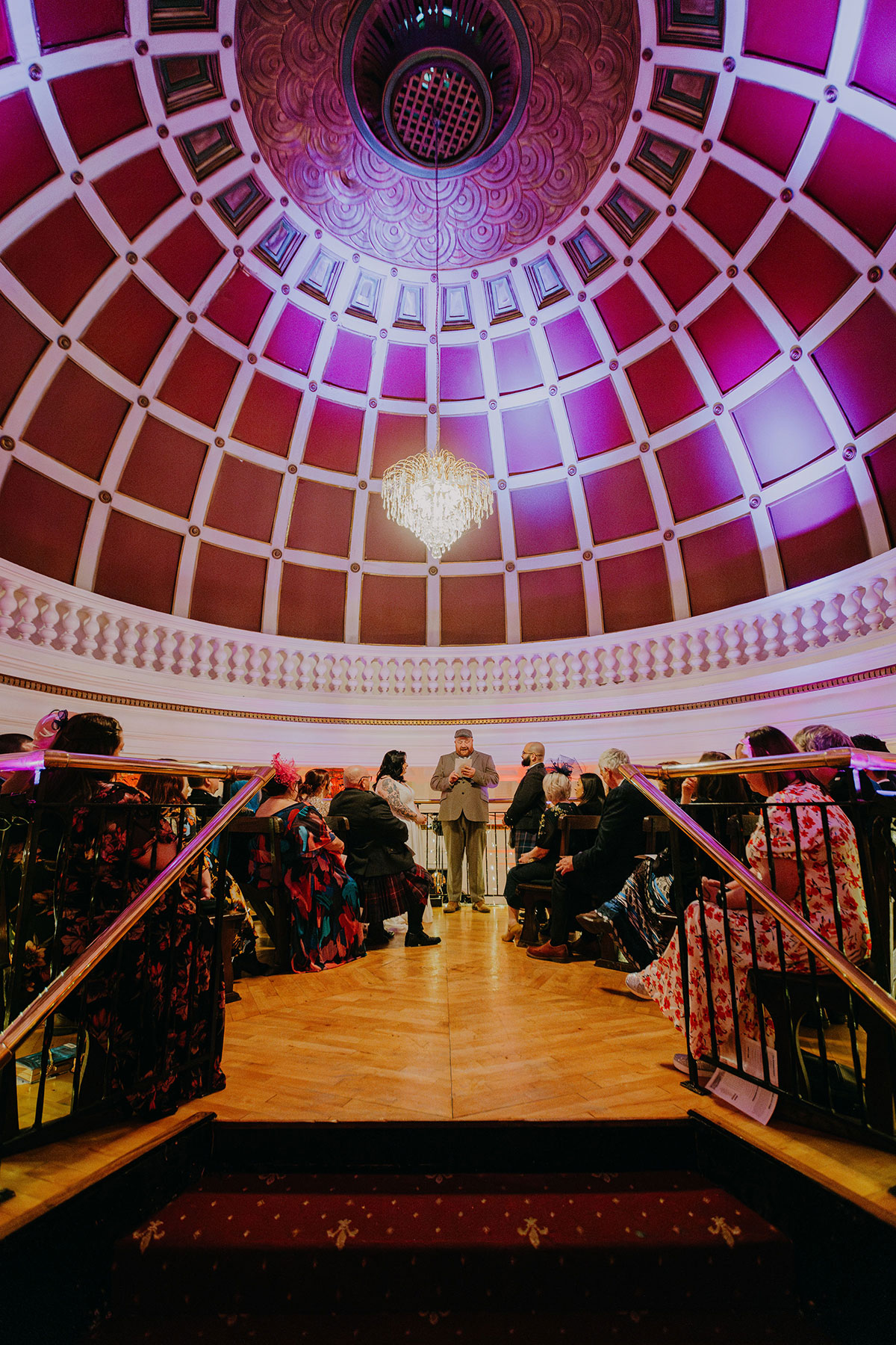 Wedding ceremony at The Savings Bank in Glasgow beneath the venue’s dramatic domed ceiling and chandelier.