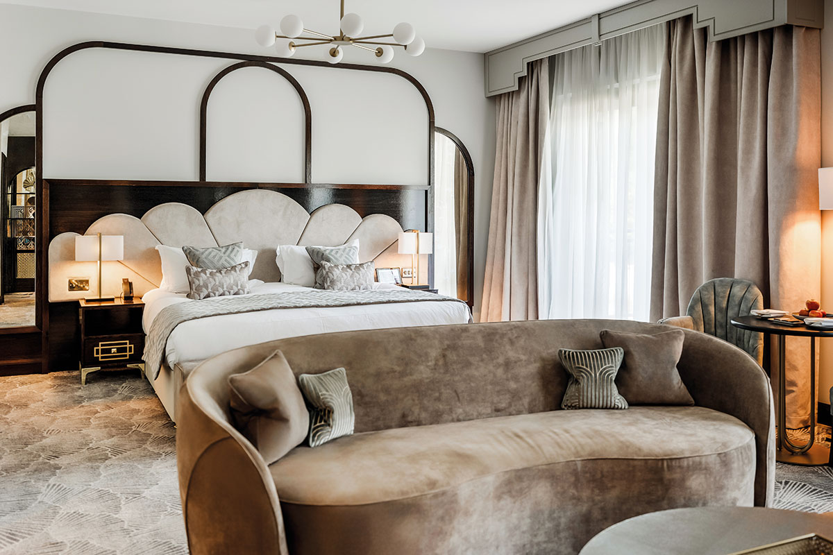 Luxury wedding suite with curved sofa and large bed, ideal getting-ready space at Scottish castle wedding venue Crossbasket Castle