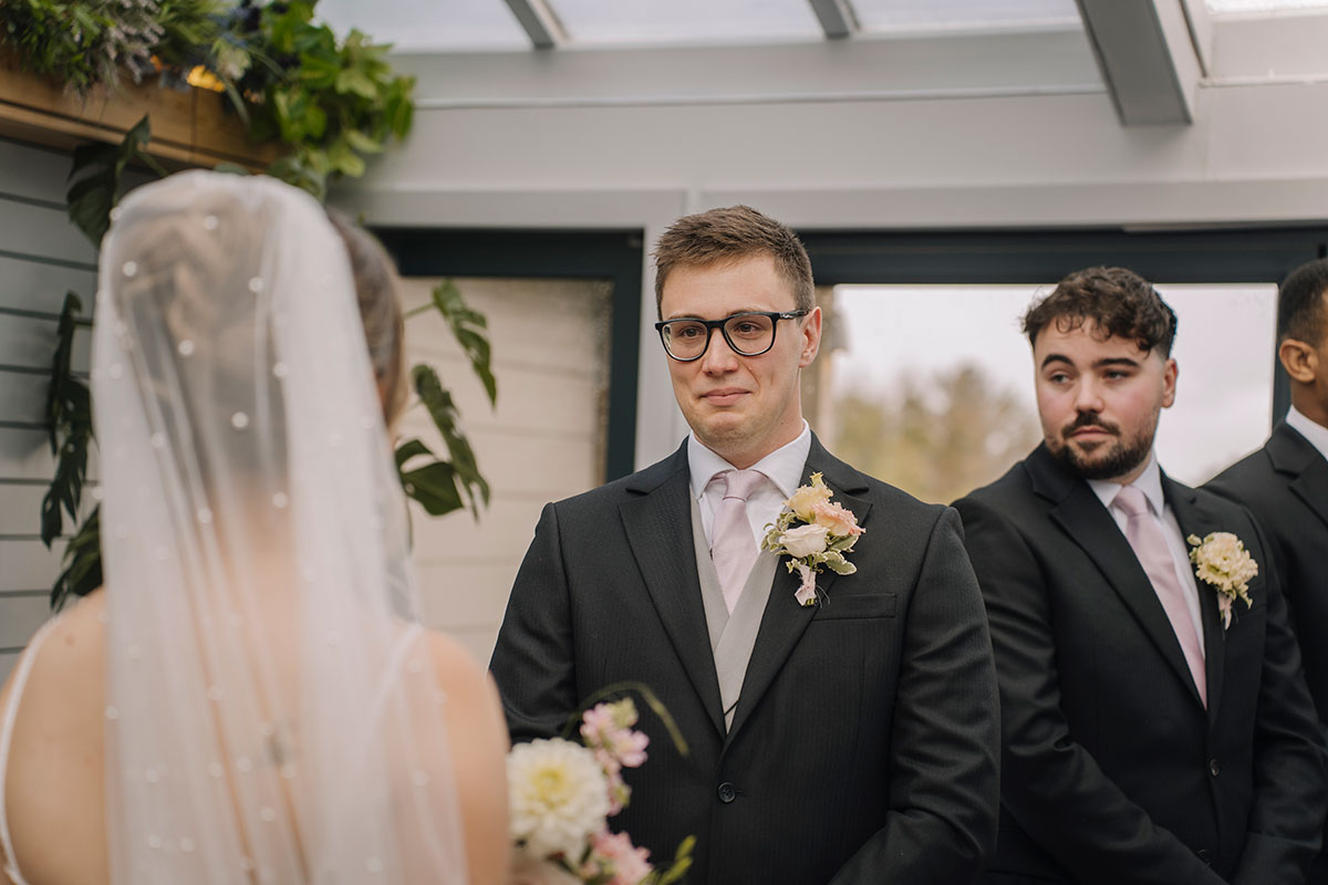 Groom smiling emotionally as he sees the bride during their indoor wedding ceremony