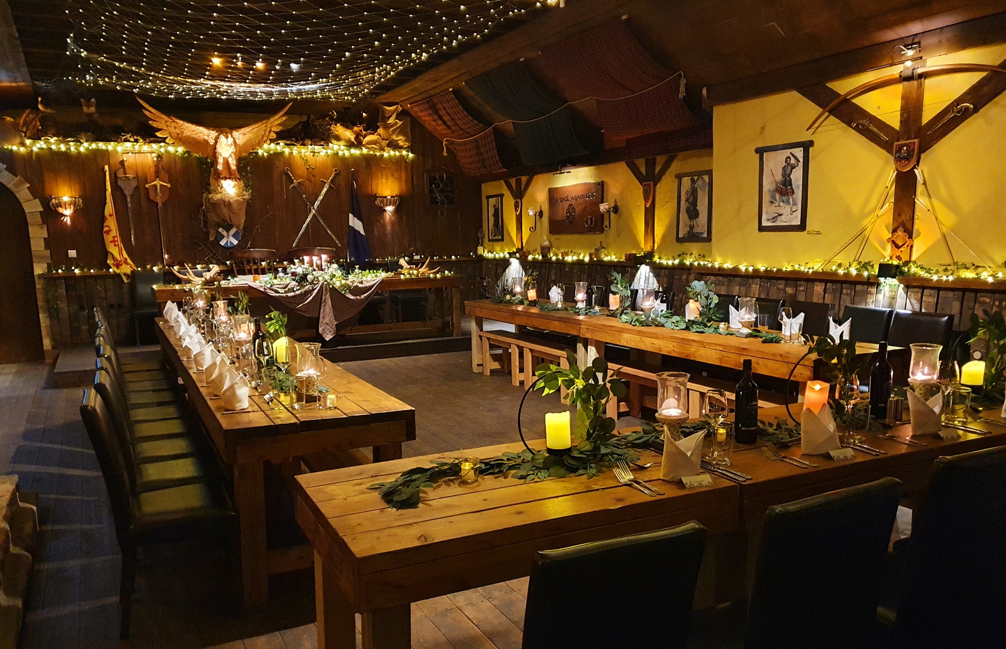 A barn with long tables with warm candle light filling the space