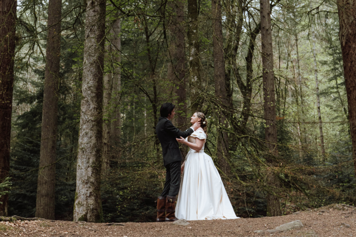 a bride and groom look into each other's eyes while standing in a forest
