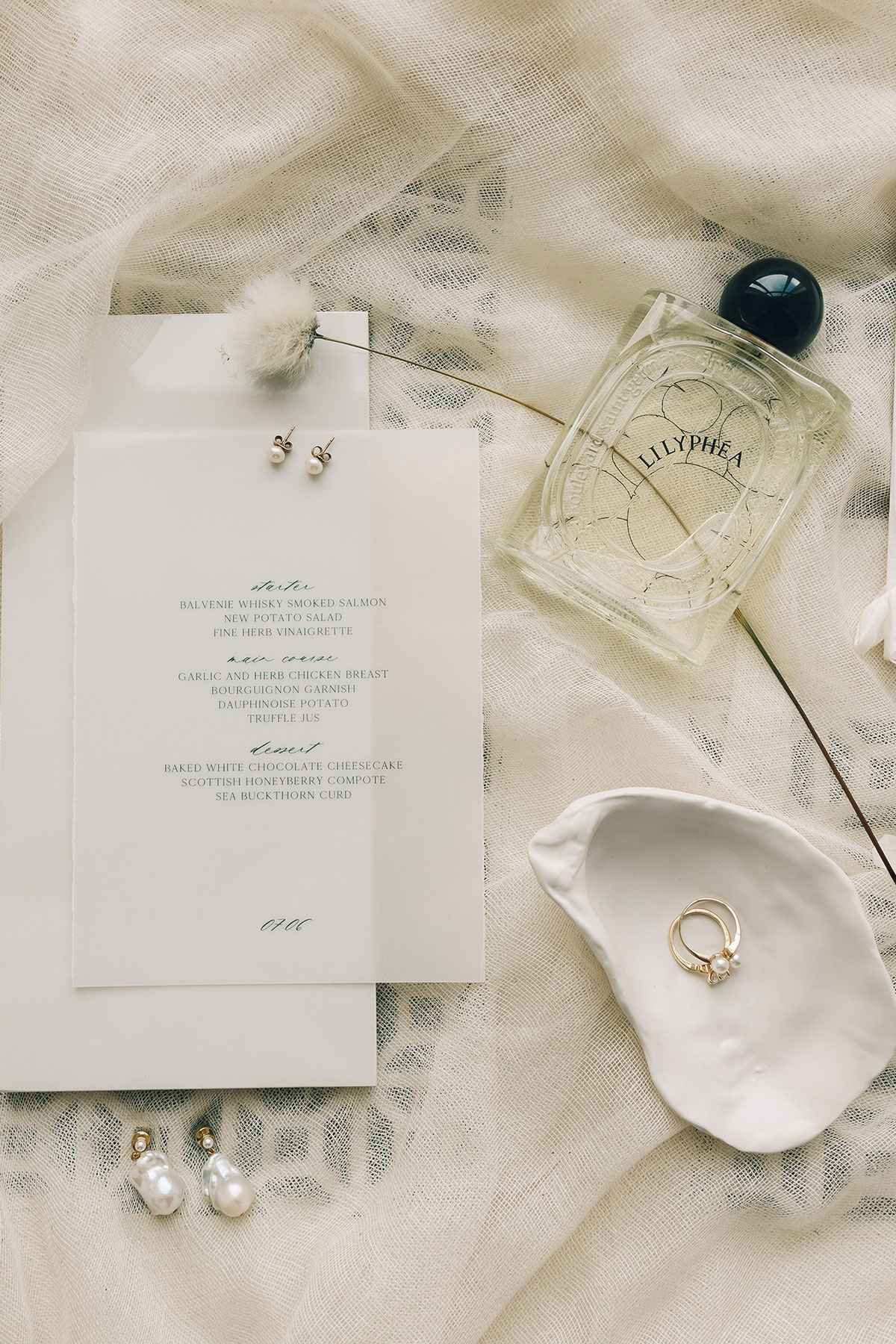 Wedding flat lay with stationery, rings and perfume on soft fabric at Gilmerton House