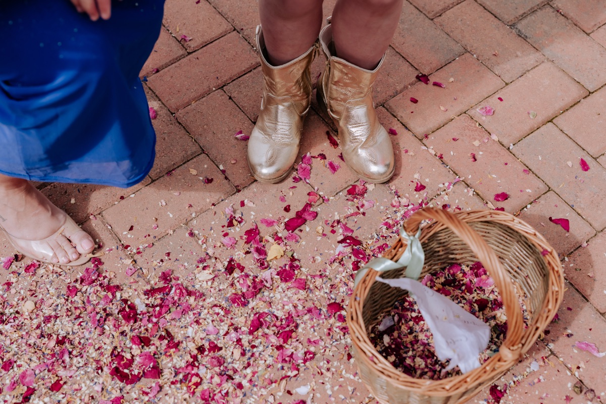 Colourful flower-petal wedding confetti scattered beside a wicker basket following Hannah and Donna’s ceremony.