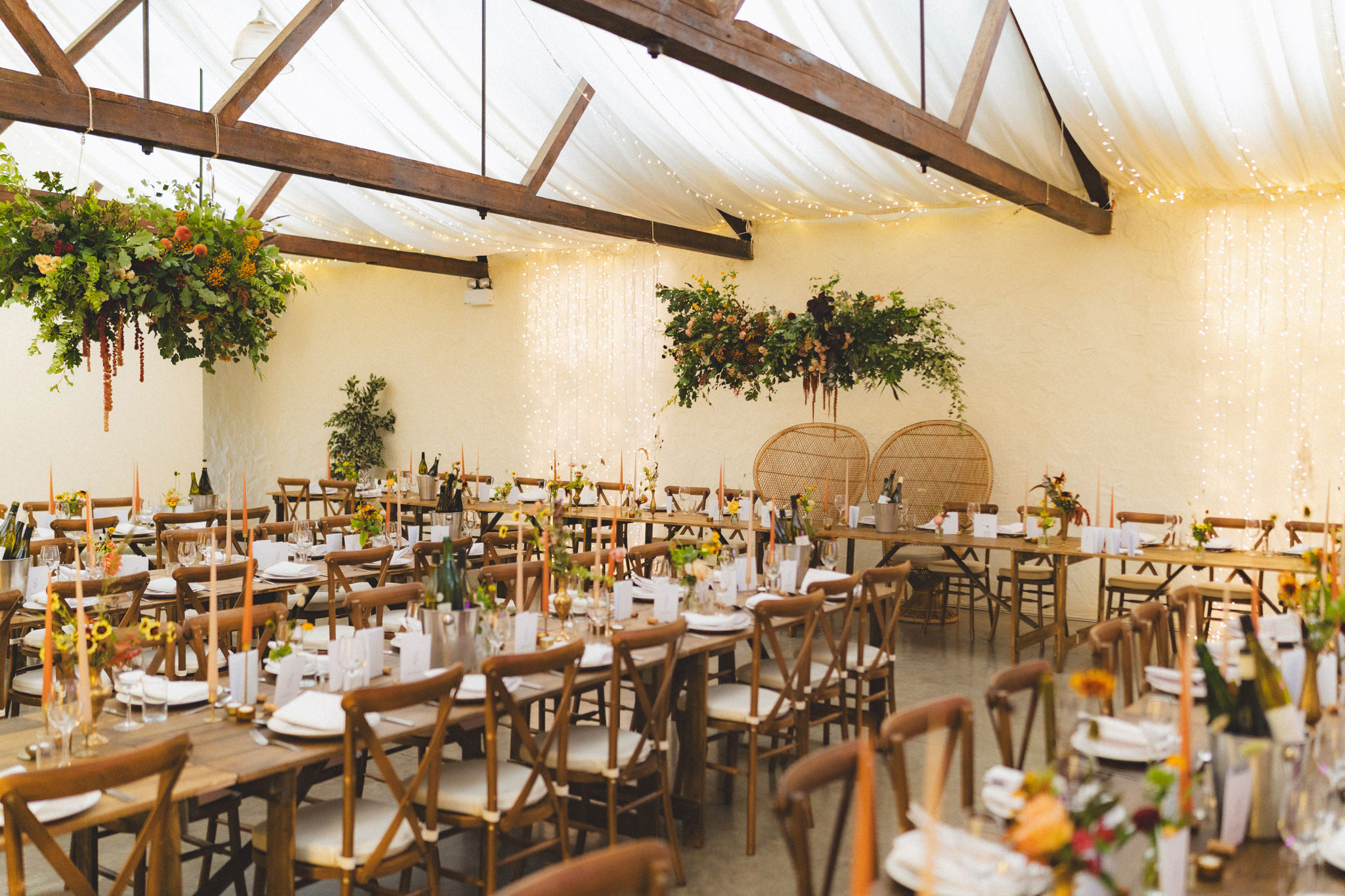 interior shot of bachilton barn set up for a wedding with long wooden tables, draped table clothes and crossback chairs