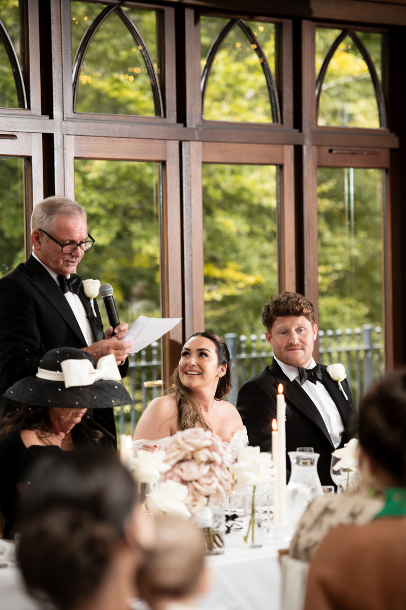 Bride and groom listening to a wedding speech at the top table during their Crossbasket Castle reception.