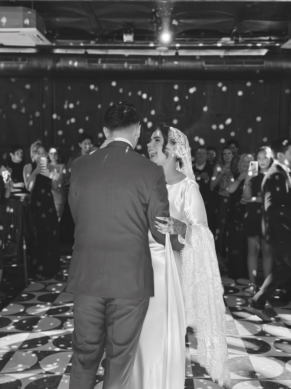 Newlyweds smiling during their first dance at The Exchange in Glasgow as guests watch from around the dancefloor.