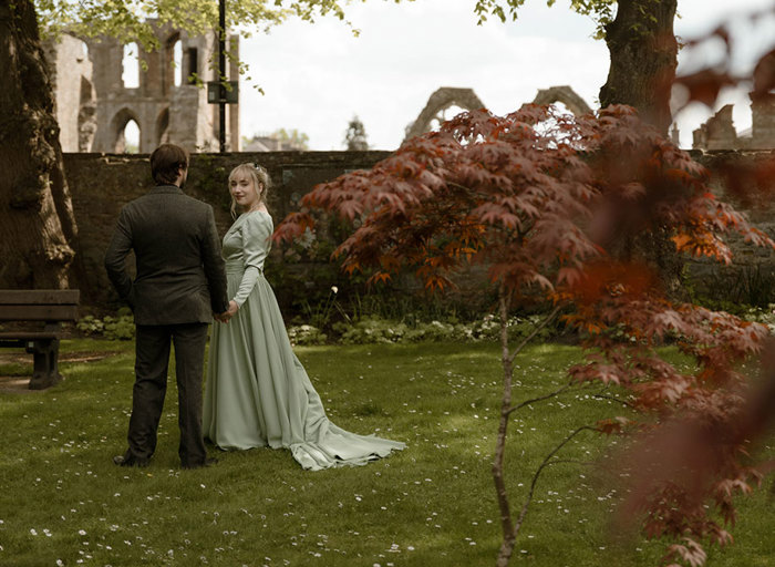 a bride and groom in the grounds of Elgin Cathedral with small red leaf tree in foreground