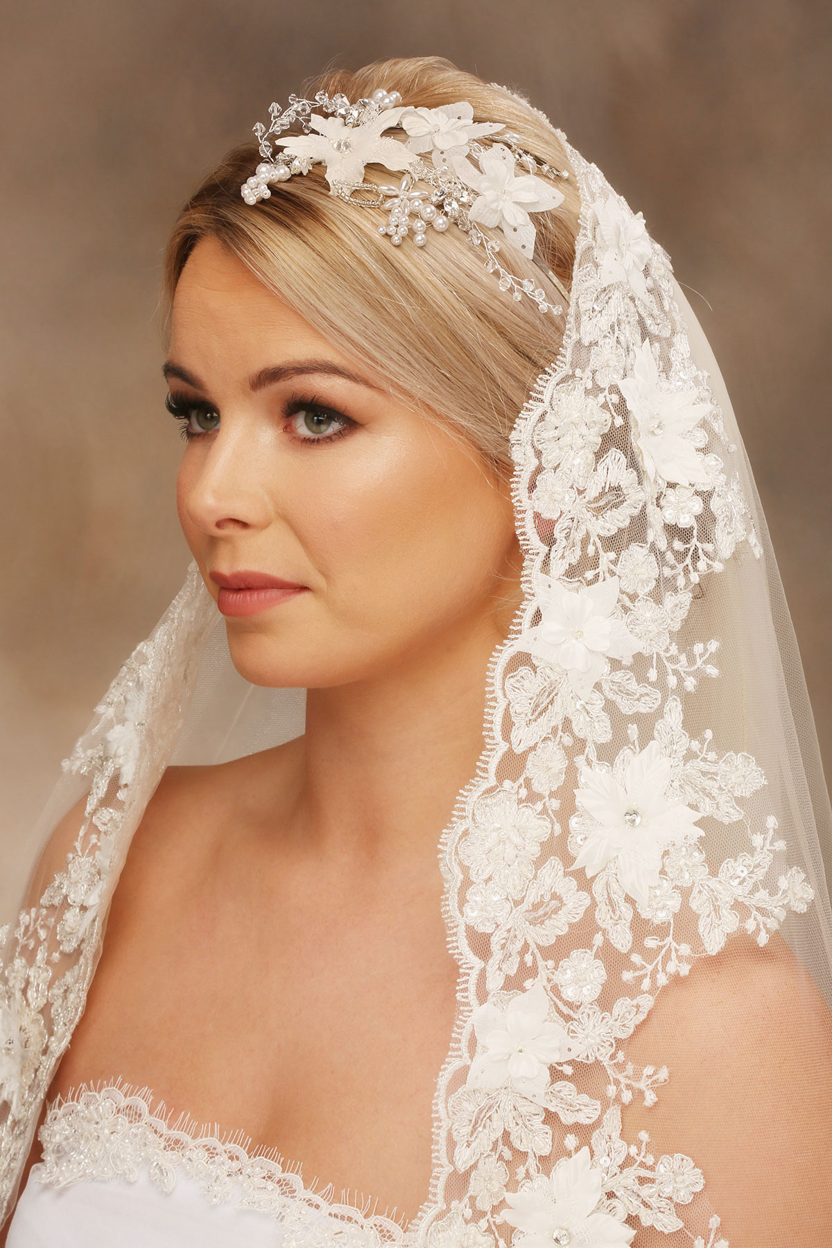 Bride wearing a floral lace wedding veil with a coordinating pearl and flower bridal headpiece by Baba-C Designs.