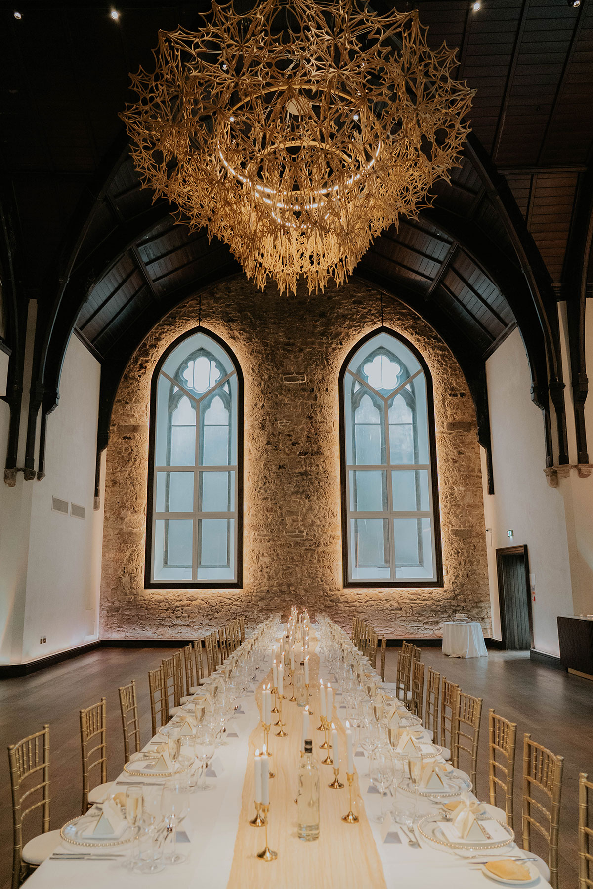 Candlelit wedding breakfast set beneath a dramatic chandelier in a historic Edinburgh wedding venue
