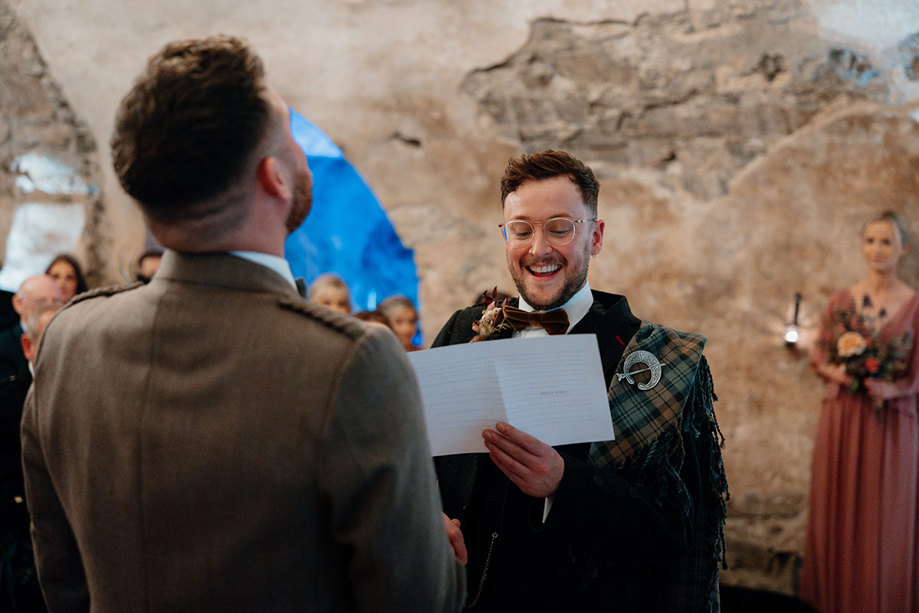 a groom reading from a folded sheet of paper during his wedding ceremony at Neidpath Castle