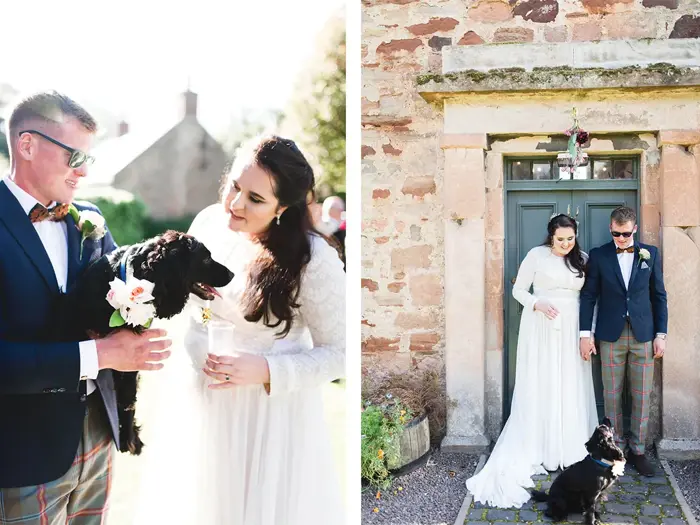 Bride and groom smile at their small black spaniel with flowers on collar