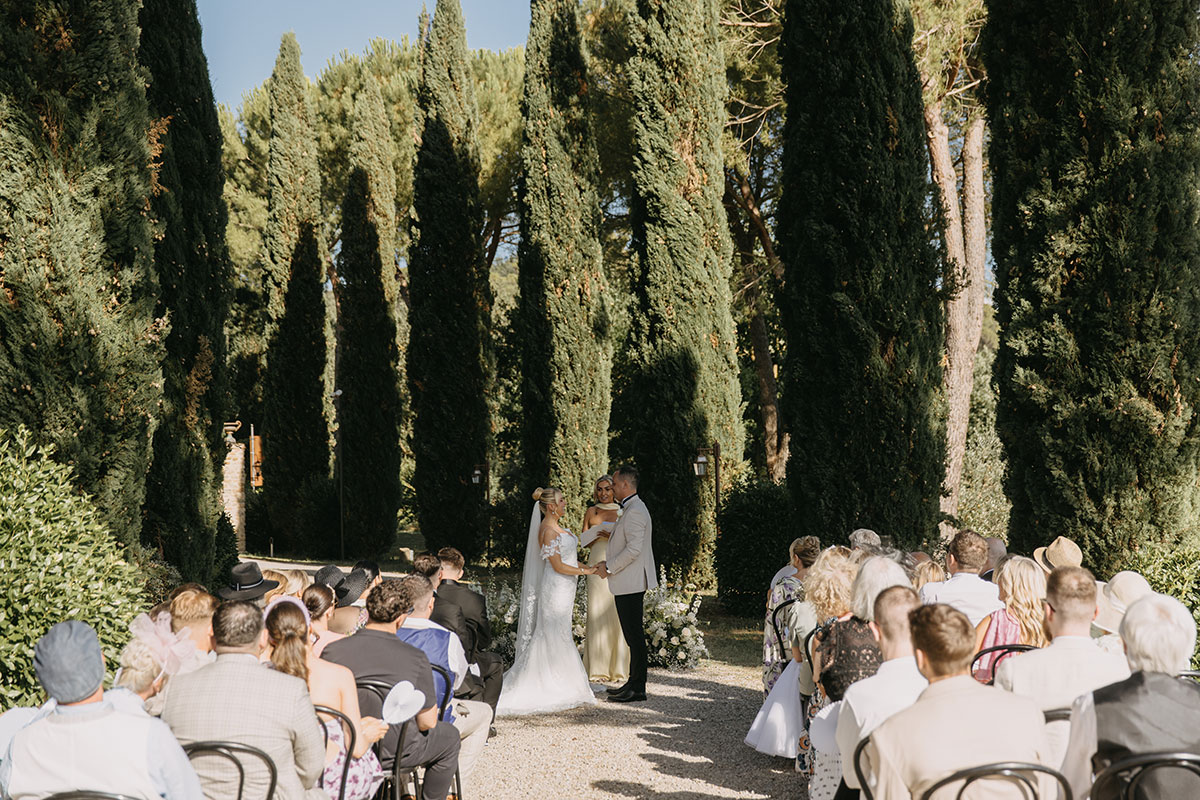 Outdoor wedding ceremony with guests seated among cypress trees at Antico Borgo San Lorenzo Tuscany