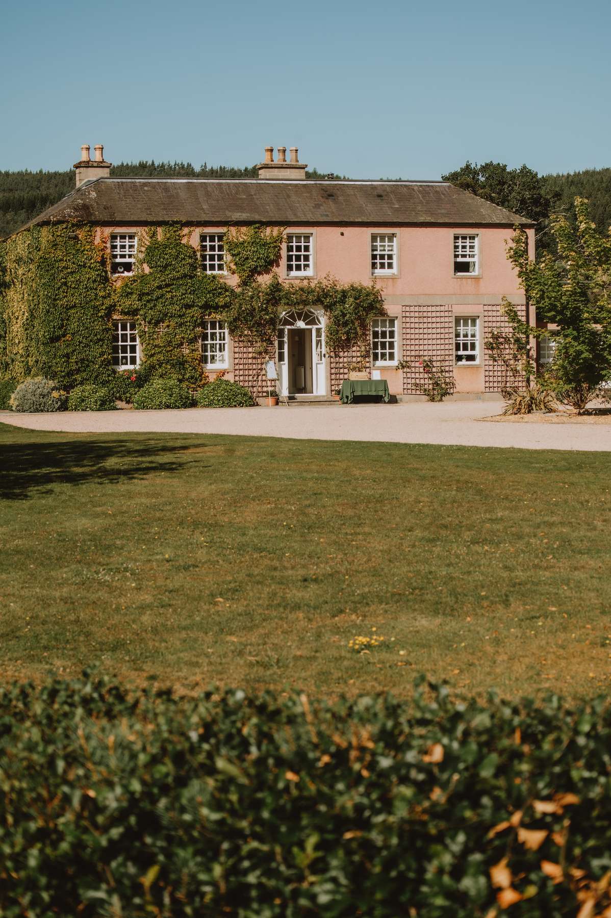 Exterior of Ballogie House wedding venue with its pink façade, ivy-covered walls and lawn