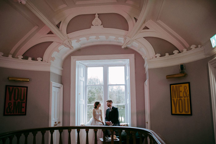 a bride and groom sitting in a window at the top of a wooden staircase at Netherbyres House