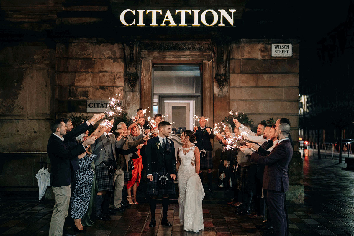 Couple coming out of Citation glasgow as friends and family hold sparklers