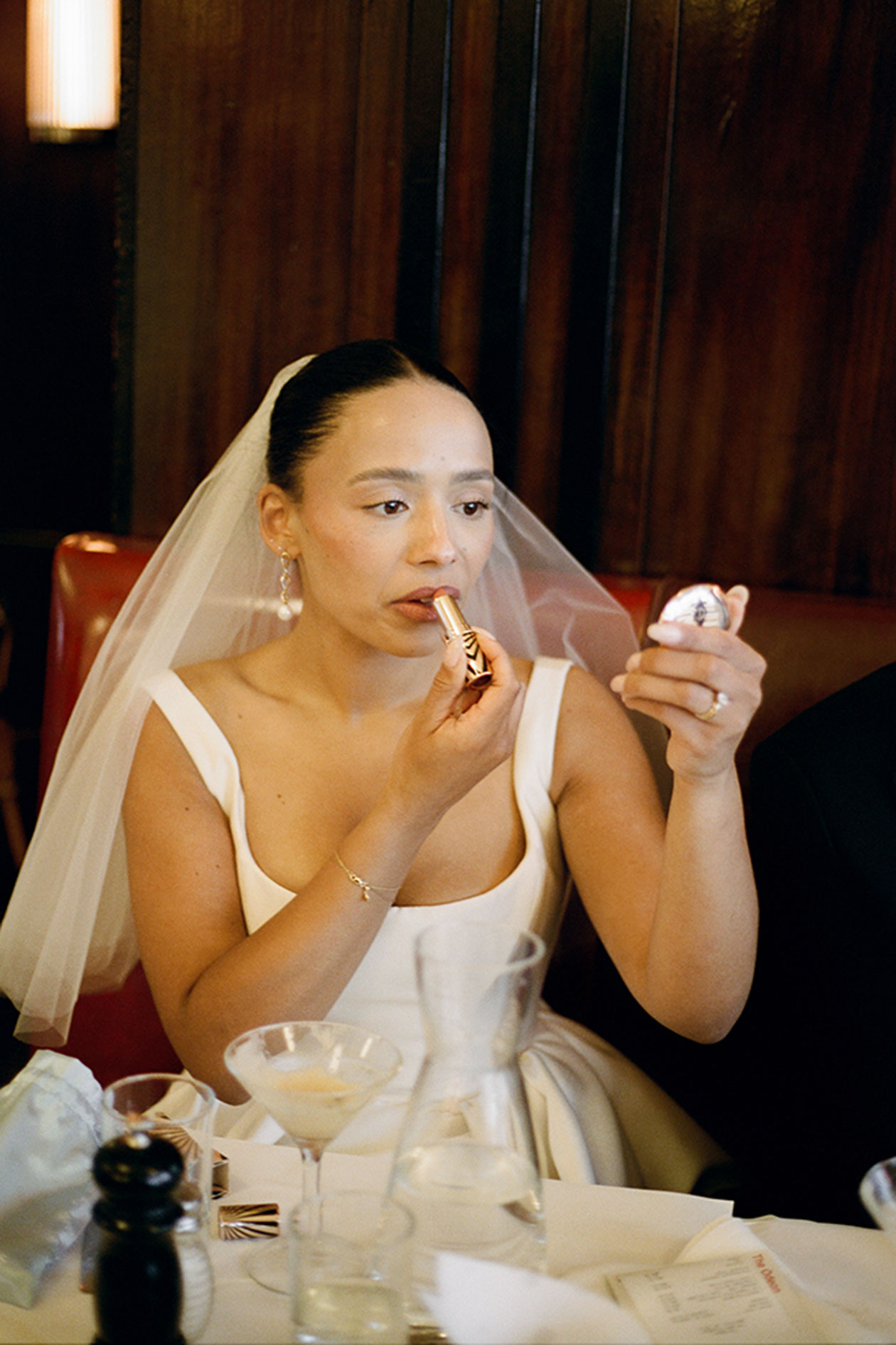 Bride applying lipstick at wedding dinner table during New York elopement celebration