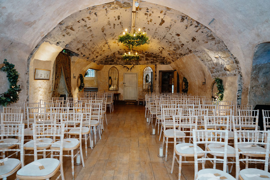 rows of Chiavari wedding chairs set for a wedding ceremony in a stone arch room at Neidpath Castle