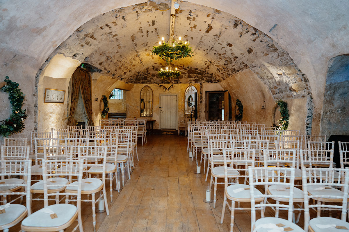 rows of Chiavari wedding chairs set for a wedding ceremony in a stone arch room at Neidpath Castle
