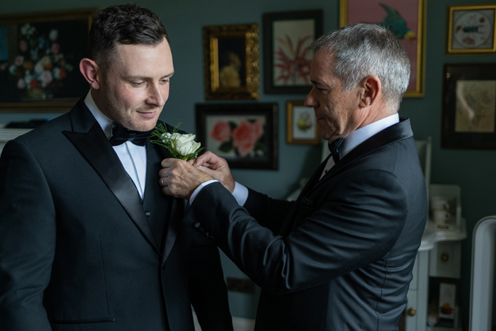 Man fixes grooms buttonhole to his lapel