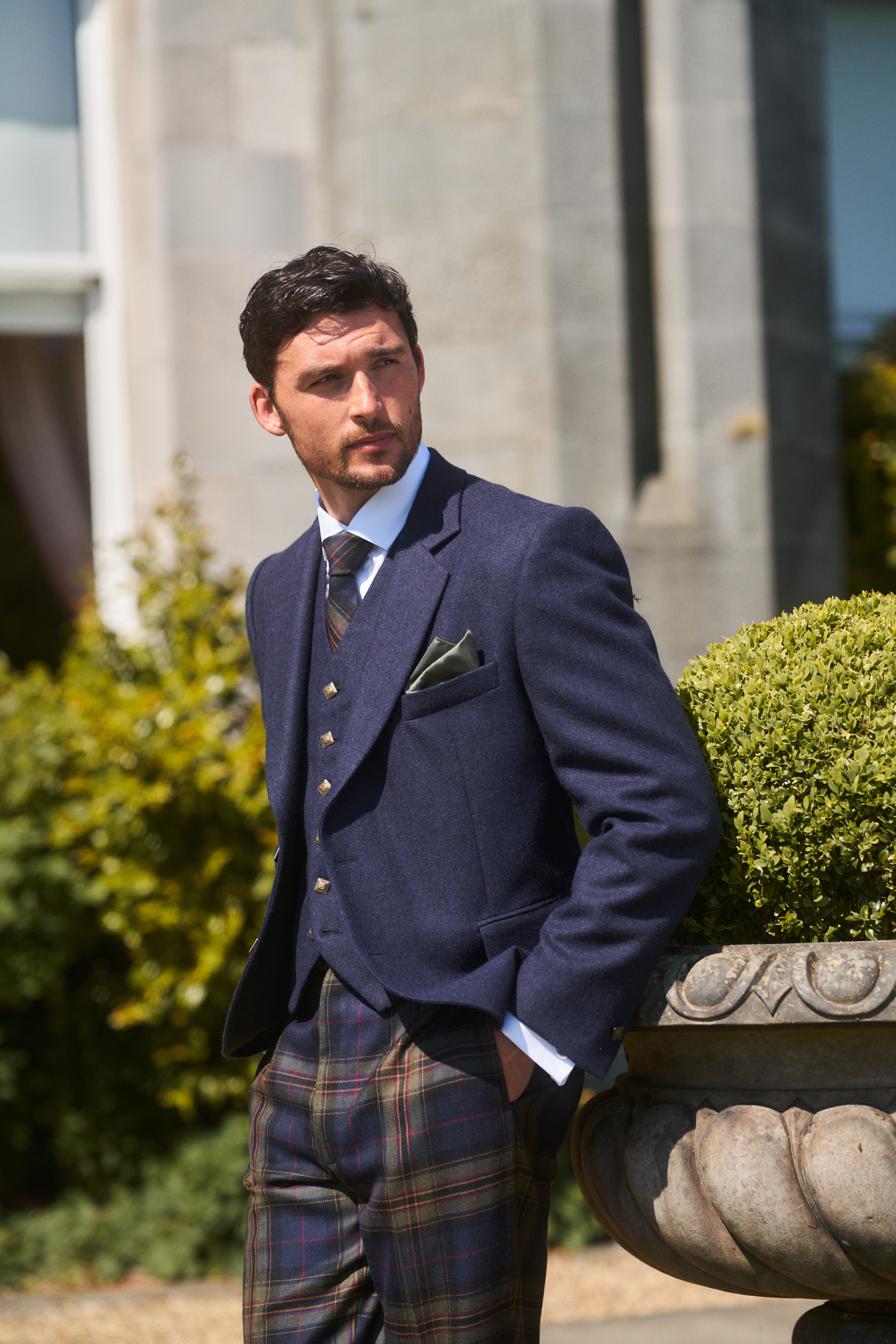 groom stares directly at camera while wearing navy jacket paired with mccalls highlandwear's tartan trews