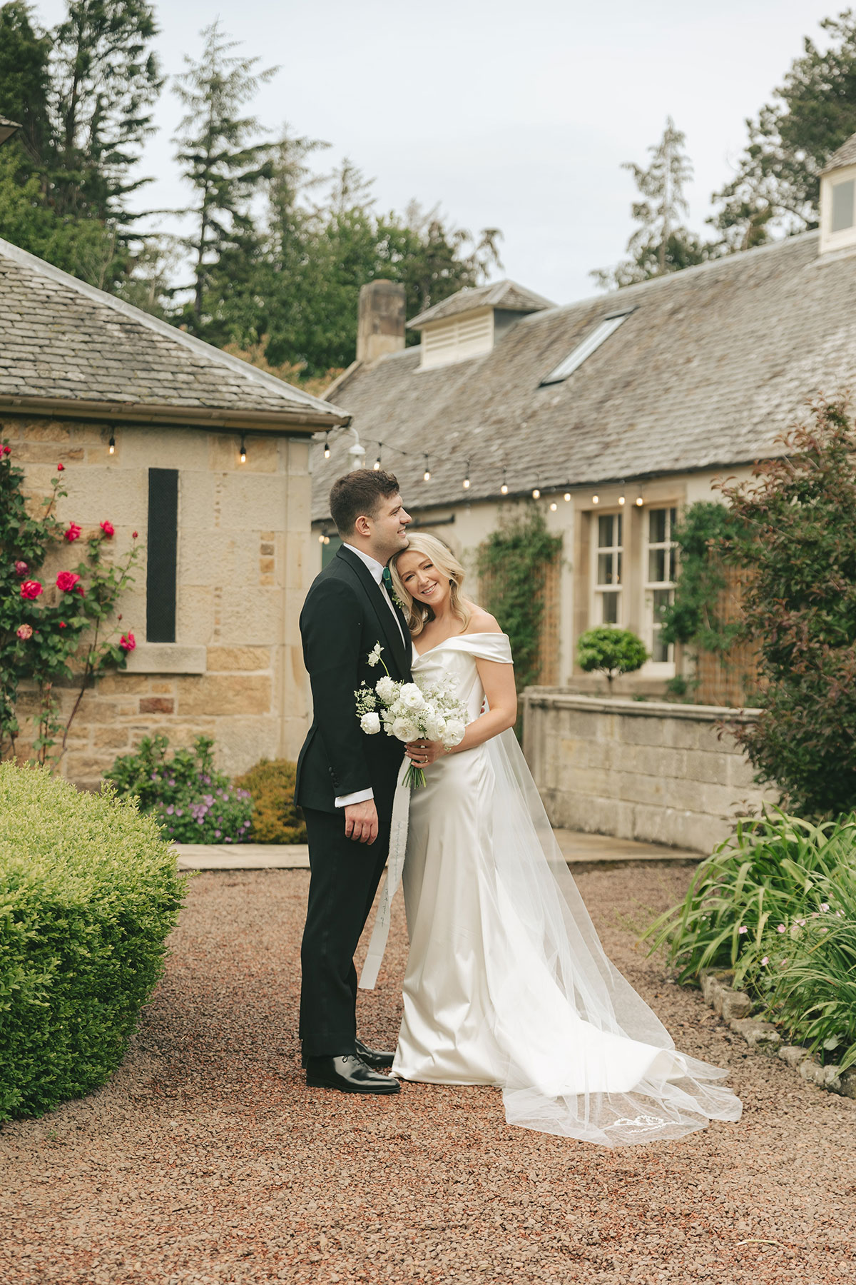 Bride and groom posing in courtyard garden at Gilmerton House East Lothian country house