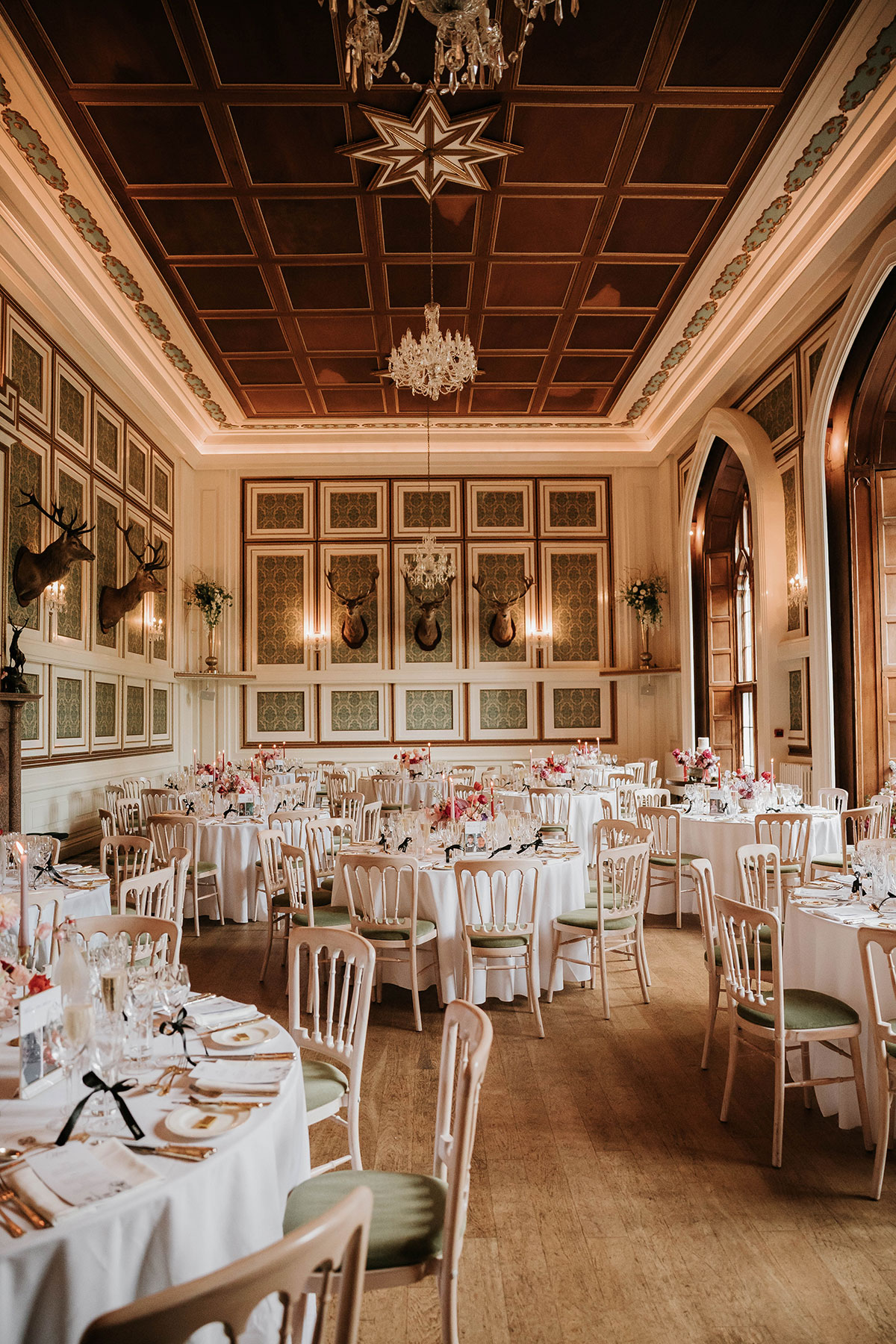 Drumtochty Castle Aberdeenshire wedding reception room set for dinner with round tables, chandeliers and elegant décor